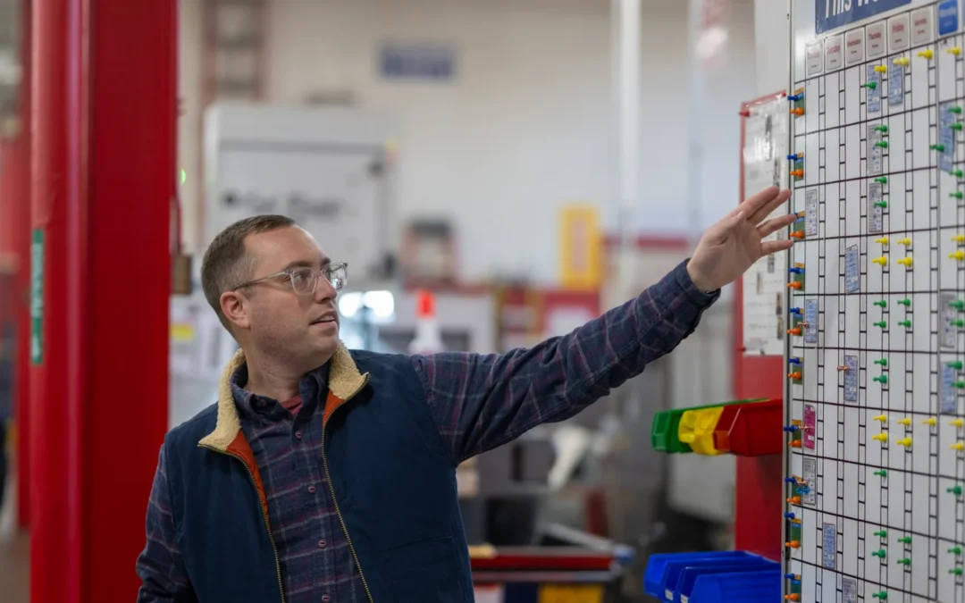 Colin Valliere presents Micron's machining schedule board in shop tour.